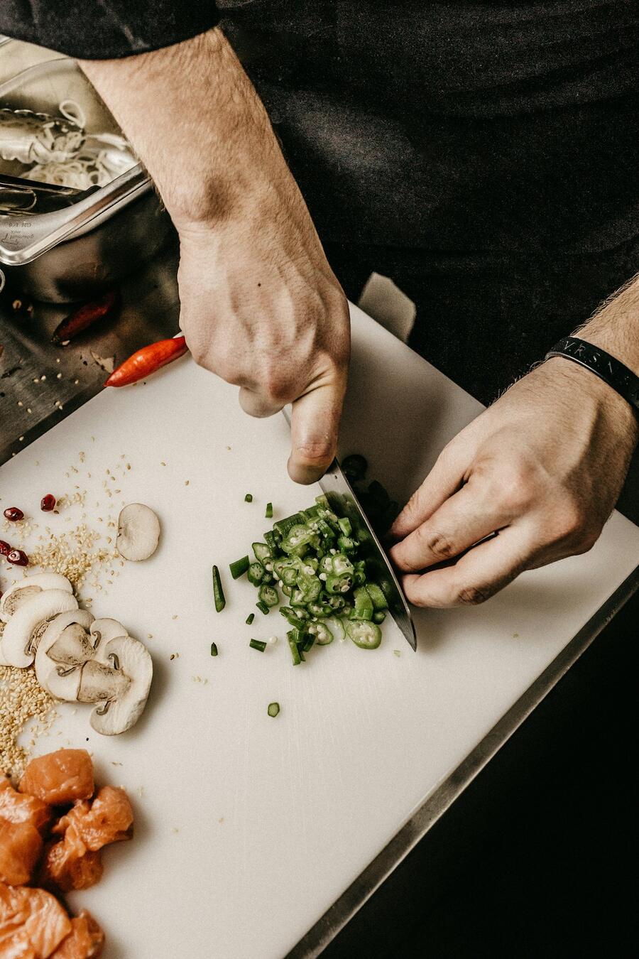 Chef chopping fresh herbs on a wooden board